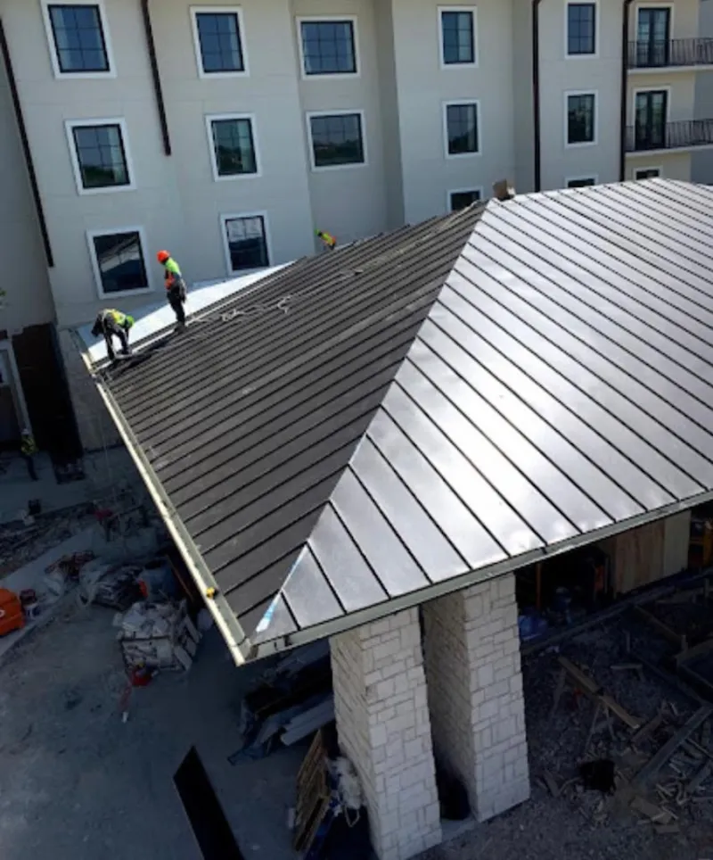 Crew installing standing seam metal roof panels on a commercial project in Dallas